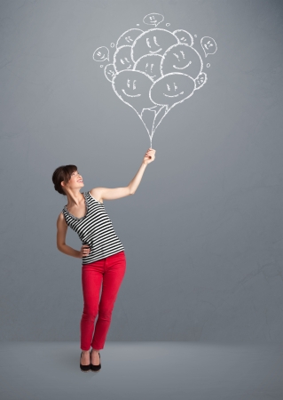 Happy young woman holding smiling balloons drawingの写真素材