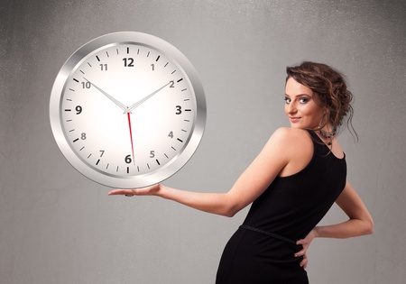 Attractive young lady holding a huge clockの写真素材