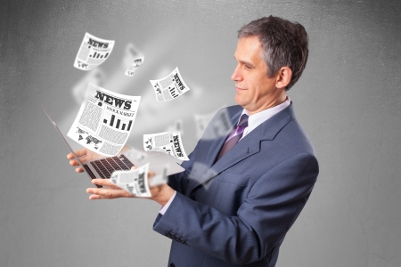 Handsome middle aged businessman holding notebook and reading the explosive newspaperの写真素材