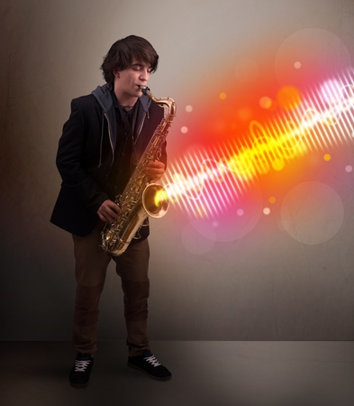 Attractive young man playing on saxophone with colorful sound wavesの写真素材