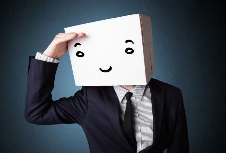 Businessman standing and gesturing with a cardboard box on his head with smiley faceの写真素材
