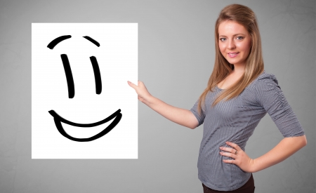 Attractive young woman holding smiley face drawingの写真素材