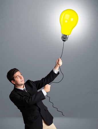 Handsome young man holding light bulb balloonの写真素材