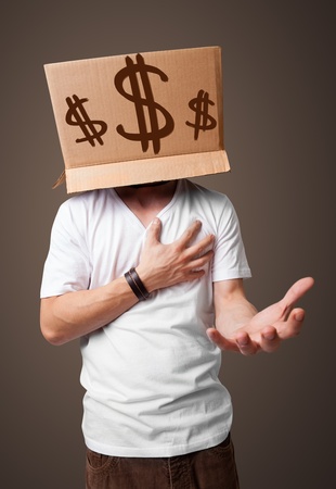 Young man standing and gesturing with a cardboard box on his head with dollar signsの写真素材
