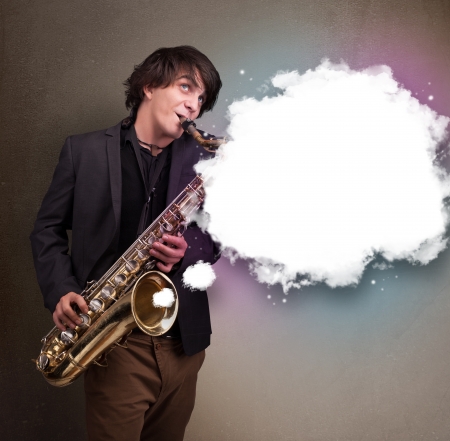 Handsome young man playing on saxophone with copy space in white cloudの写真素材