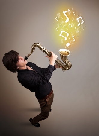 Handsome young musician playing on saxophone with musical notesの写真素材