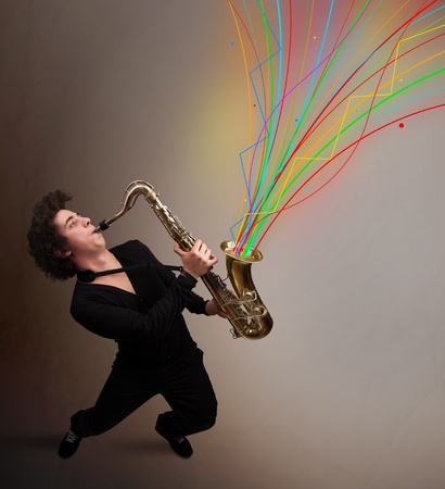 Attractive young musician playing on saxophone while colorful abstract lines explodingの写真素材
