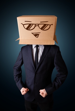 Businessman standing and gesturing with a cardboard box on his head with smiley faceの写真素材