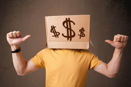 Young man standing and gesturing with a cardboard box on his head with dollar signsの写真素材