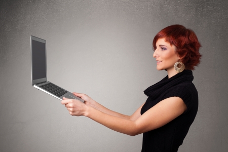 Pretty young woman holding modern laptotの写真素材