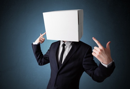 Businessman standing and gesturing with a cardboard box on his headの写真素材