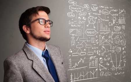Attractive young man looking at stock market graphs and symbolsの写真素材