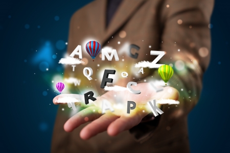 Young business man in suit presenting magical clouds with letters and balloons conceptの写真素材