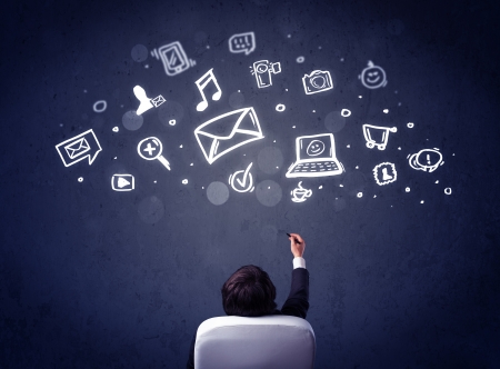 Young businessman sitting in office chair with sketched multimedia icons above his headの写真素材