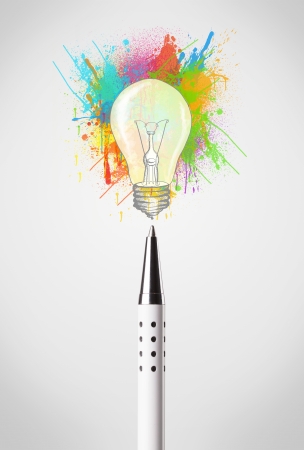 Pen close-up with colored paint splashes and lightbulb conceptの写真素材
