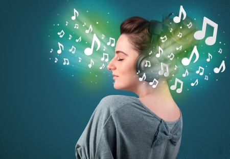 Pretty young woman with headphones listening to music, glowing notes conceptの写真素材
