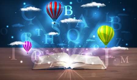 Open book with glowing fantasy abstract clouds and balloons on wood deckの写真素材