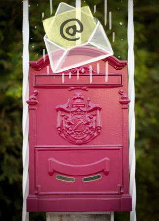 White envelope with email sign dropping into mailboxの写真素材