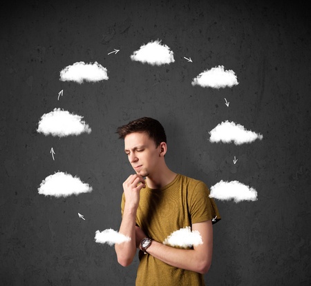 Thoughtful young man with drawn clouds circulating around his headの写真素材