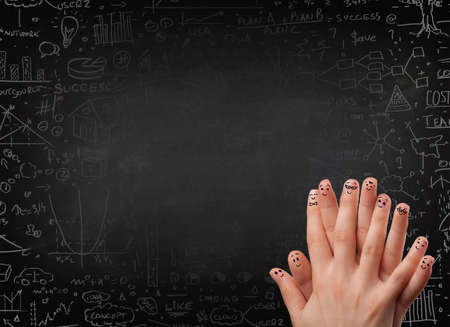 Happy finger smileys faces on hand with black chalkboard in backgroundの写真素材