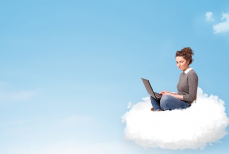 Pretty young woman with laptop sitting on cloud with empty spaceの写真素材