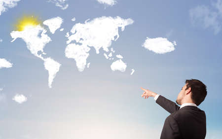 Businessman looking at world clouds and sun on blue skyの写真素材