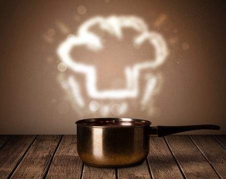 Chef hat coming out from cooking pot on wooden tableの写真素材