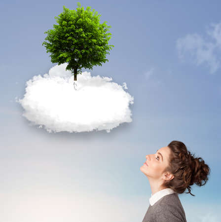 Young girl pointing at a green tree on top of a white cloud conceptの写真素材
