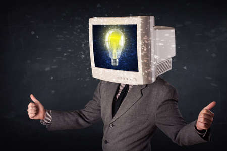 Business man with a pc monitor head and idea light bulb glowing in the displayの写真素材