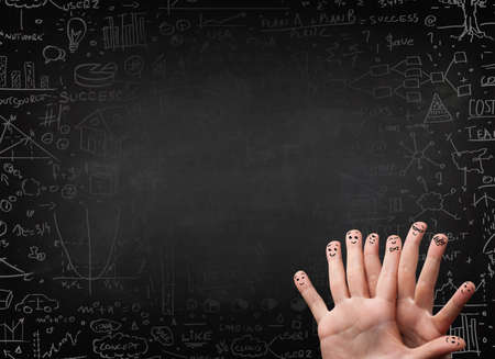 Happy finger smileys faces on hand with black chalkboard in backgroundの写真素材