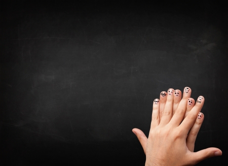 Happy cheerful smiley fingers looking at empty black chalboardの写真素材