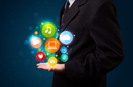 Young business man in suit presenting colorful technology icons and symbolsの写真素材