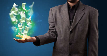 Young businessman holding glowing paper moneys in his handの写真素材