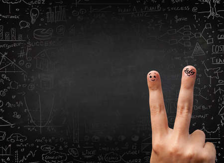 Happy finger smileys faces on hand with black chalkboard in backgroundの写真素材