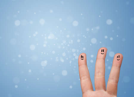 Happy finger smileys faces on hand with empty blue bokeh backgroundの写真素材