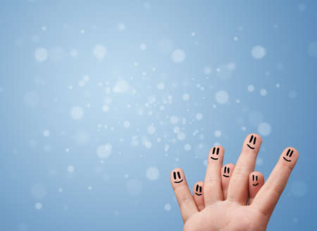 Happy finger smileys faces on hand with empty blue bokeh backgroundの写真素材