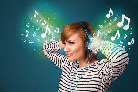 Pretty young woman with headphones listening to music, glowing notes conceptの写真素材