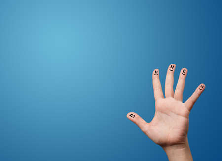 Happy smiley face fingers cheerfully looking at empty blue background copy spaceの写真素材