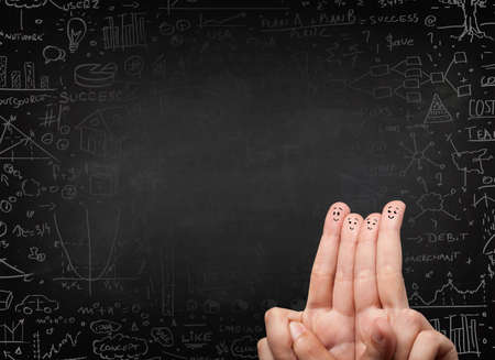 Happy finger smileys faces on hand with black chalkboard in backgroundの写真素材