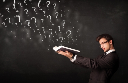 Confused man reading a book with question marks coming out from itの写真素材