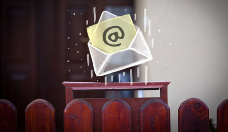 White envelope with email sign dropping into mailboxの写真素材