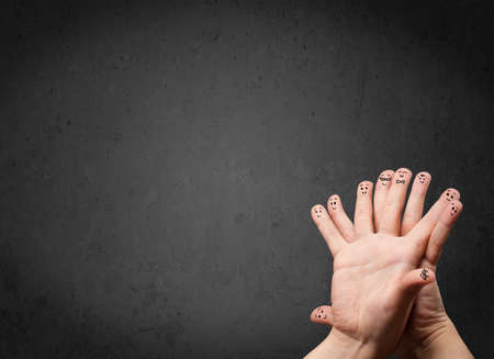 Happy finger smileys faces on hand with empty copy space dark background