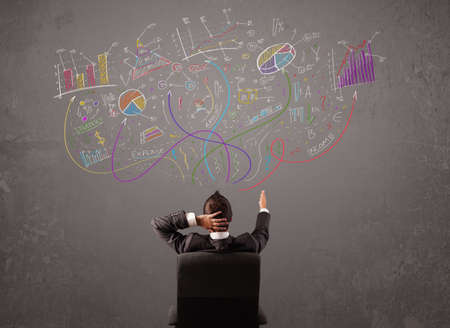 Young business man looking at sketches of graphs and symbols on the wall