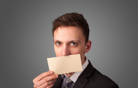 Businessman holding white card at front of her lips with copy space on gradient backgroundの写真素材