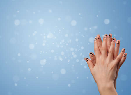 Happy finger smileys faces on hand with empty blue bokeh backgroundの写真素材