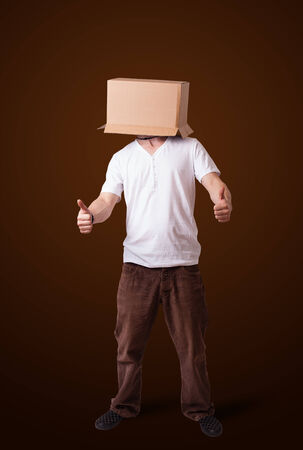 Young man standing and gesturing with a cardboard box on his headの写真素材