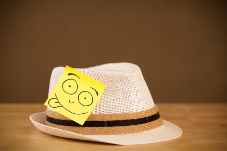Drawn smiley face on a post-it note sticked on a hatの写真素材