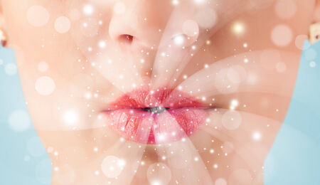 Pretty woman lips blowing abstract white lights - close upの写真素材