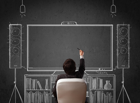 Young businessman sitting and enjoying home cinema system sketched on a chalkboardの写真素材