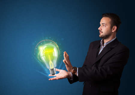 Young businessman holding glowing lightbulb in his handの写真素材